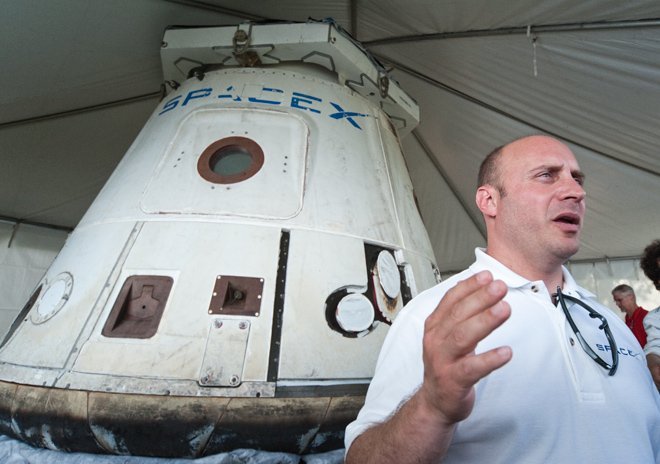 Önde SpaceX kurucusu eski NASA Astronotu Garret Reisman. Arkada ise Dragon Kapsülü.